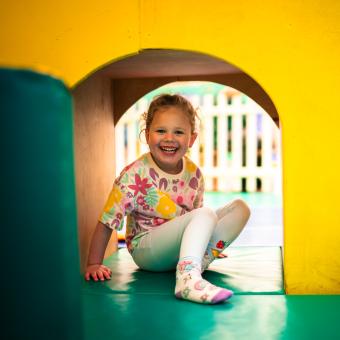 Girl hiding in archway under a slide in soft play
